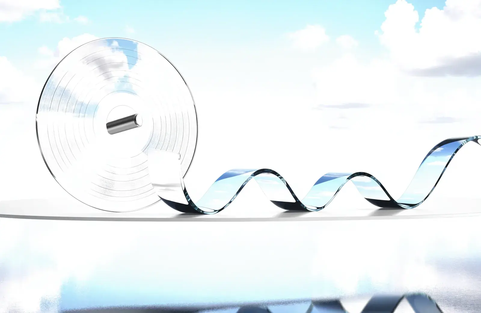 A transparent record and smooth glass ribbon beside sky-blue water.